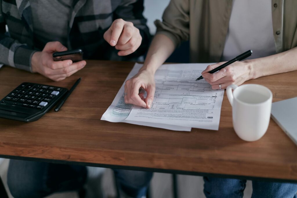 pexels-photo-6963909-6963909 Couple managing finances at home with a calculator, smartphone, and documents.